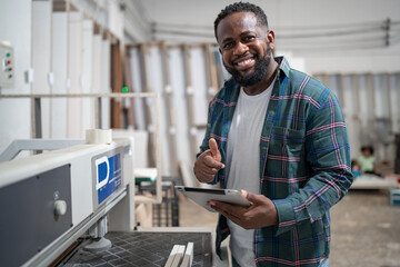 Portrait African American carpenter use tablet computer with wood sheet at wood factory	