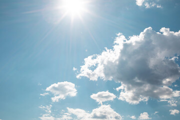 Natural blue background. Clear blue sky with white clouds and bright sunlight. Summer sky