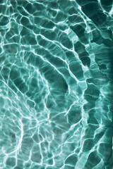 Abstract nature textured background, water waves in the pool with sun reflection, clear green water