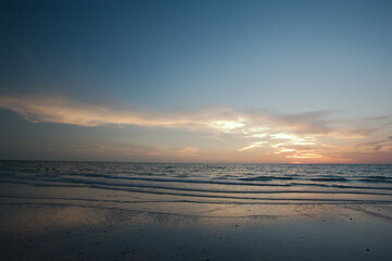 Fototapeta na wymiar Sunset dark at Florida beach. Calm water with yellow sky from sun. 