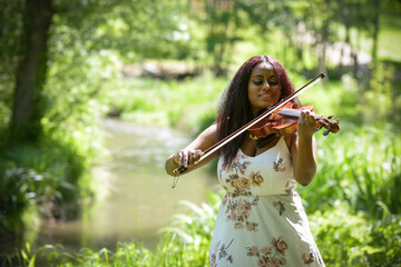 young woman playing the violin in a park in France
