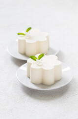 Vanilla cream pudding, Panna Cotta, decorated with a small cute white flower. On a plate. White background