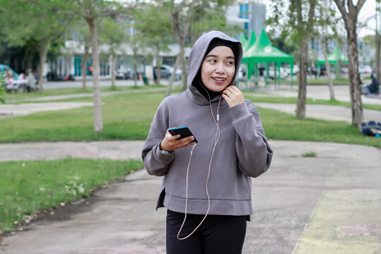 Asian young muslim women using phone after doing stretching exercise at city park - Powered by Adobe