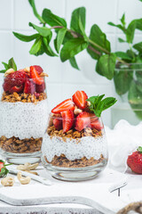 Granola with yogurt, chia and strawberries in a glass on a white background