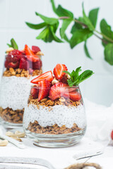 Granola with yogurt, chia and strawberries in a glass on a white background