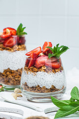 Granola with yogurt, chia and strawberries in a glass on a white background
