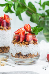 Granola with yogurt, chia and strawberries in a glass on a white background