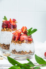 Granola with yogurt, chia and strawberries in a glass on a white background