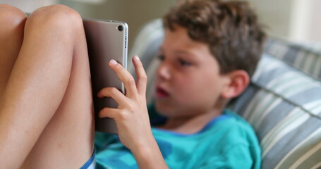 Child playing game on tablet device. Young boy hypnotized by video-game