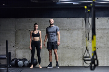 Muscular man and fit woman in a conversation before commencing their training session in a modern gym.
