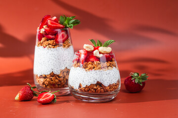 Granola with yogurt, chia and strawberries in a glass on a bright background