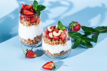 Granola with yogurt, chia and strawberries in a glass on a bright background