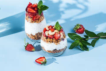 Granola with yogurt, chia and strawberries in a glass on a bright background