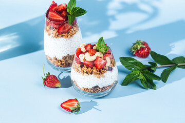 Granola with yogurt, chia and strawberries in a glass on a bright background