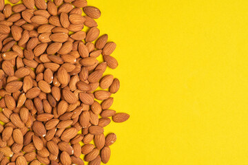 Handful of almonds yellow background.