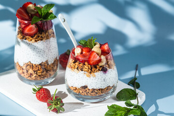 Granola with yogurt, chia and strawberries in a glass on a bright background