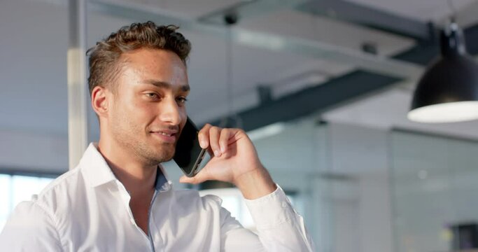 Happy biracial businessman talking on smartphone at office, in slow motion