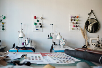 Focus on workplaces of seamstresses or tanners with electric equipment, lamps and colorful spools of threads on the wall in workshop