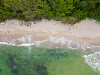 From above, the mesmerizing beach unfolded with golden sand caressed by turquoise waves. Lush green...