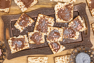 Tray with pieces of matzah covered with chocolate paste and gray and pink sprinkles for Jewish holiday Pesach.