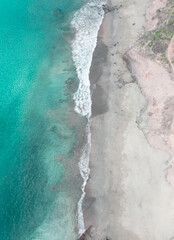 Drone shot from above of the light blue turquoise water of Tenerife beach, half water half white sand