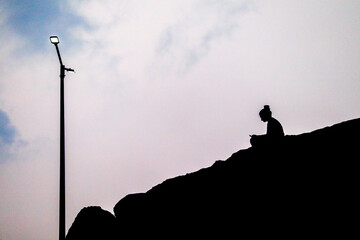 the silhouette image of a sad girl sitting and in street light