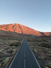 Long straight street leading to a huge vulcano lightened by the sunset