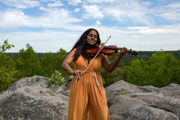Lovely black woman playing violin in the forest