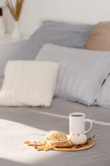 Fototapeta na wymiar cup of coffee on wooden tray on bed in cozy bedroom