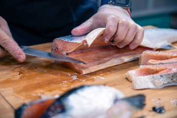 Chef preparing a salmon fish by gutting and filleting at the kitchen