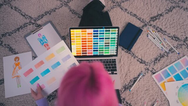 Top view of woman with pink hair working on laptop as fashion designer, artist