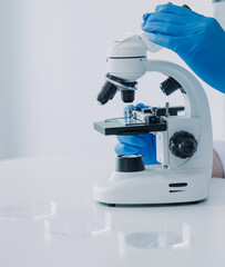 medical or scientific researcher researching and experimenting Multi-colored solution, vial and microscope In the laboratory or in the laboratory by wearing blue gloves and white clothing completely.