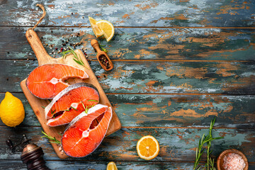 Two fresh fish salmon pieces. Raw Salmon steaks with lemons and spices on wooden board.