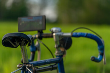 Old bicycle with very modern mobile phone on handlebar on spring color meadow