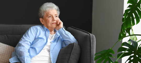 Thoughtful senior woman sitting on sofa at home