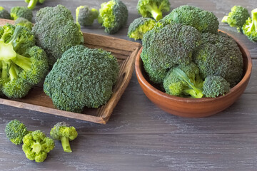 fresh broccoli on a wooden background close-up. background with broccoli in a wooden bowl and tray.