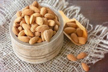 almond seeds in a wooden bowl and spoon on the table close-up. almond top view close-up. background with raw almonds.