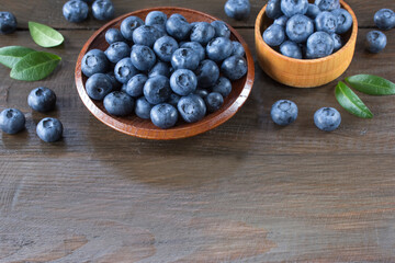 fresh blueberries in a wooden bowl and bowl on a wooden table close-up. background with ripe fresh blueberries.