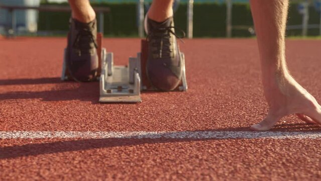 Caucasian male runner preparing for the race, putting hands on the starting line with feet on the starting block, close up shot.