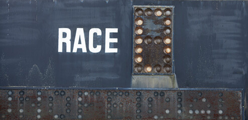Weathered, rusty horse racing sign with the word Race printed next to lights
