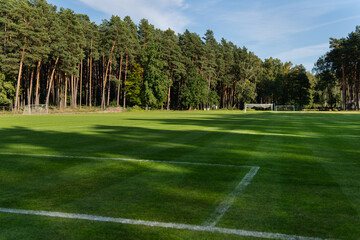 Fototapeta premium Local football. Soccer freshly cut grass field near pine forest, street game.