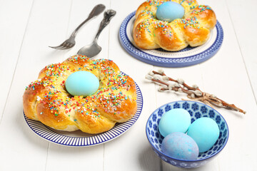Table setting with tasty Italian Easter bread and willow branches on white wooden background