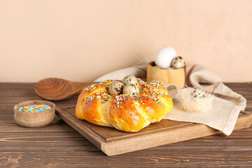 Board with tasty Italian Easter bread, colorful sprinkles and eggs on wooden table