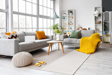 Interior of bright living room with cozy sofas and coffee table near big window
