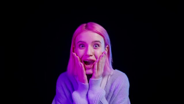 Stylish woman with tongue piercing showing surprised face on black background