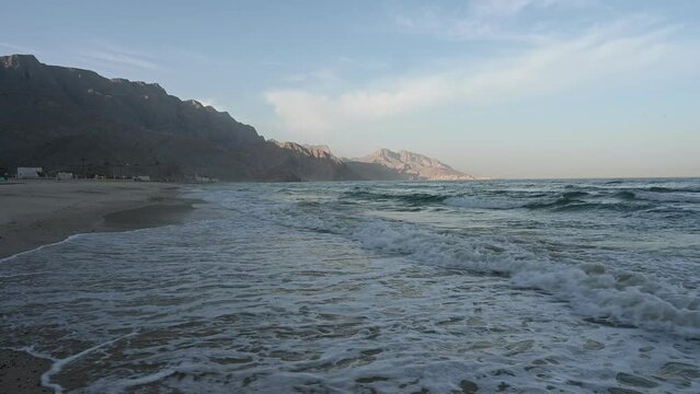 A 4K Video of  Waves Crashing on a Sandy Beach with Hajar Mountains in the background. Taken at Khasab Oman