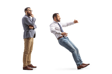 Full length profile shot of a pensive man standing behind a man falling