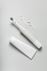 Electric toothbrush with paste and toothpicks on grey background