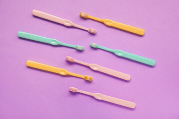 Many plastic toothbrushes on purple background