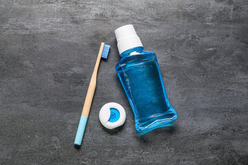 Dental floss with blue bamboo toothbrush and mouthwash on black grunge background